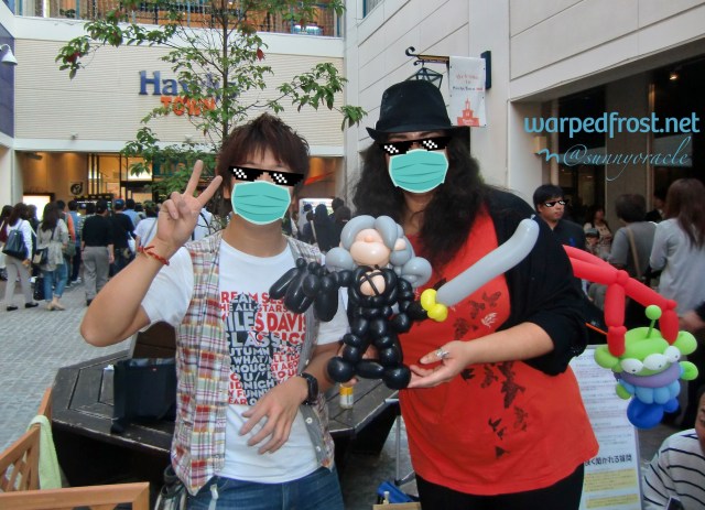 Photo of the balloon artist and I posing with Balloon Seph between us. The artist chose to depict Seph with his One Wing and Masamune.