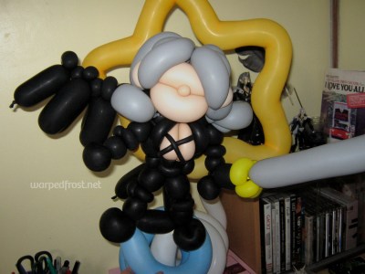 Balloon Seph indoors, sitting atop a bookcase with all my GACKT DVDs, other Sephiroth figures, and a black feather I had picked up (probably dropped by a crow).