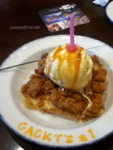 Apple cobbler with ice cream on top and a candle, with the message "Gackt's #1" written in frosting on the lip of the bowl.