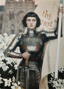 Illustration showing Joan of Arc, identified by her short dark hair, suit of armor, the white banner she is holding up with her left hand, and a sword (pointed downward) in her right. She stands in a field of lilies. In the background is the facade of a Gothic church.