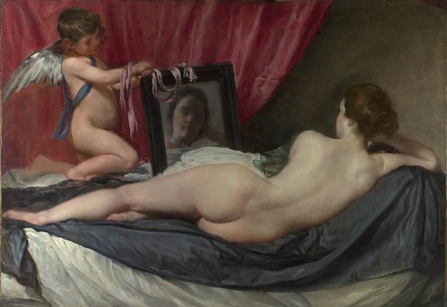 Photo of Diego Velazquez's oil painting "Rokeby Venus," which shows a nude brunette from behind. She is reclining on a bed looking at her reflection in a mirror which is held by Cupid.